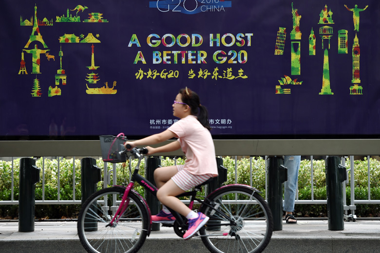 Ein Mädchen fährt an einem Poster zum Thema G20 in Hangzhou vorbei.jpg